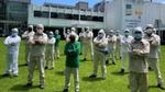 Empleados de una fábrica de Unilever con ropa protectora y mascarillas posan juntos sobre el césped.